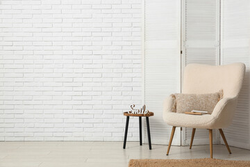 Interior of living room with folding screen, armchair and table