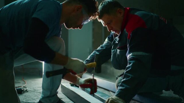 workers install flooring, two craftsmen carefully position floor sections inside, two skilled workers carefully align and secure floor panels during interior construction