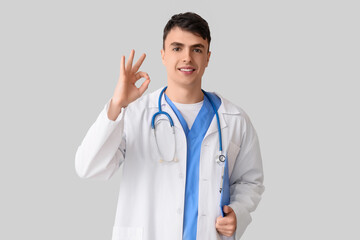 Male doctor showing OK on light background