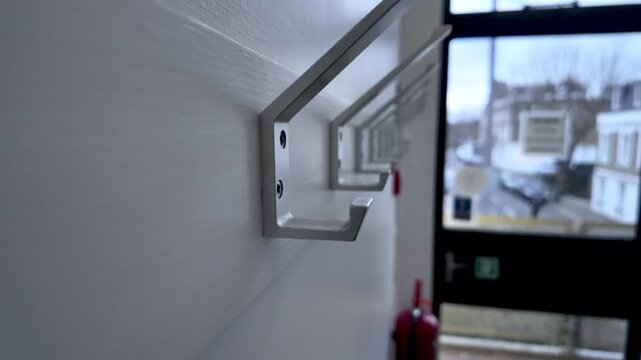Modern Metal Coat Rack With Hooks Mounted On White Wall In Corridor Featuring Sleek Design And Functional Storage For Coats And Accessories In Home Interior.