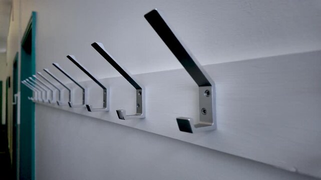 Row of Metal Coat Hooks Mounted on White Wall in Corridor Featuring Modern Design and Practical Storage Solutions for Entryways and Public Spaces