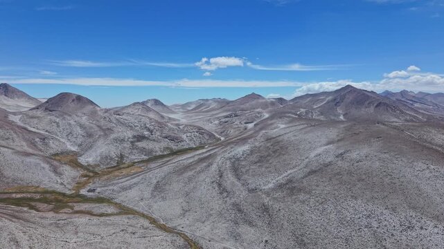 The drone pans across salt-covered peaks of Pachacutec and Qillqata, creating a dreamy, snow-like landscape. White salt contrasts with yellow sulphur riverbeds, forming a surreal volcanic atmosphere.