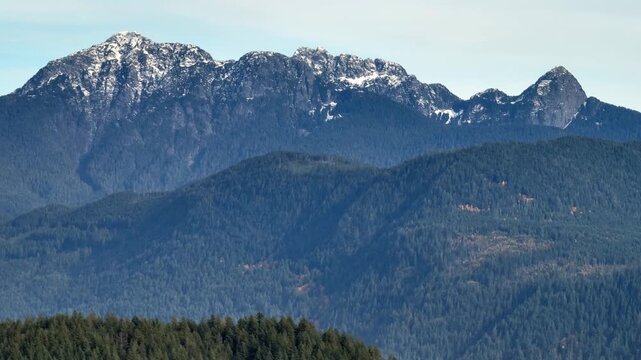 A Forested Ridgeline and Rugged Peaks Stretch Across the Burke Mountains in Canada - Aerial Drone Shot