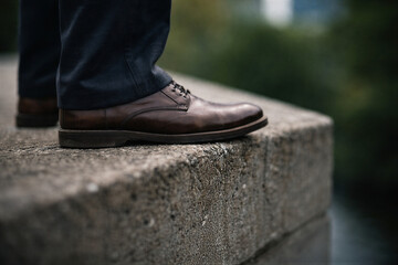 Męskie buty stojące na krawędzi betonowego murku w plenerze