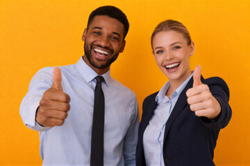 Uśmiechnięta para biznesowa pokazująca kciuk w g&oacute;rę na ż&oacute;łtym tle