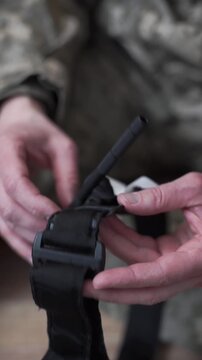A soldier examines a medical tourniquet used in combat to stop blood flow during first aid.