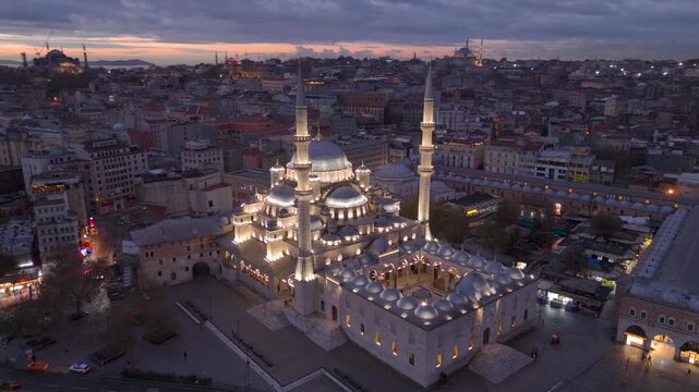 Aerial drone view of Istanbul historic Golden Horn, showing the Eminonu New Mosque or Yeni Cami, Galata Bridge, and Bosphorus at sunrise or sunset. Topkapi Palace and Hagia Sophia in the distance.