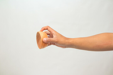 Hand holding a small round wooden object against a white background