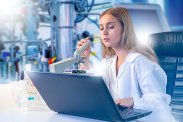 Laboratory research scientist examines samples with microscope while recording results on laptop....