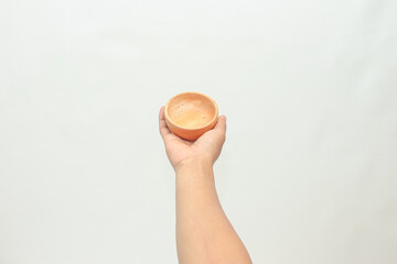 Hand holding small terracotta bowl with speckled interior against white background