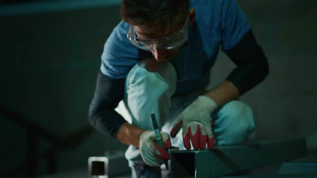 fabricator carefully trims metal edges using pliers and files indoors, craftsperson diligently smoothing metal edges with tools in controlled workshop environment