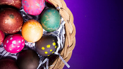 colorful easter eggs in basket with purple background