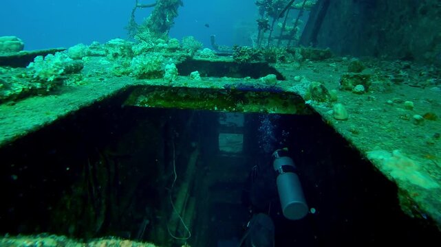 Descending from above, penetrating through window of wheelhouse of the wreck of Salem Express ferry, scuba diver swims inside rooms, Slow motion of diver swims inside cabin of sunken ship