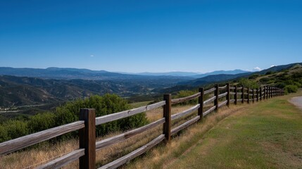 Fototapeta premium Scenic Wooden Fence Zigzagging Through Panoramic Hills Under Clear Blue Sky
