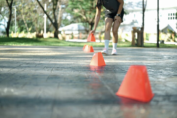 Woman placing training cones on pavement to prepare agility and speed workout, focus on training cones