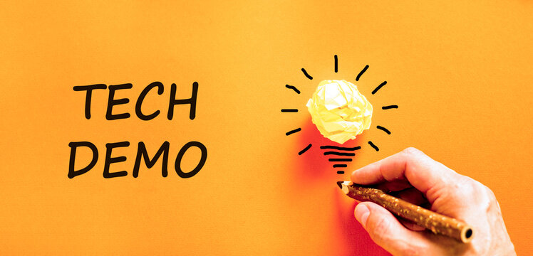 Tech demo symbol. Concept word Tech demo on beautiful orange paper. Businessman's hand. Light bulb icon. Beautiful orange paper background. Business tech demo concept. Copy space.