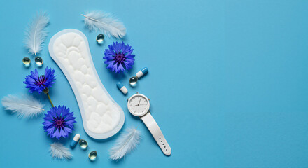Feminine hygiene pad with flowers, clock, and pills on blue background  