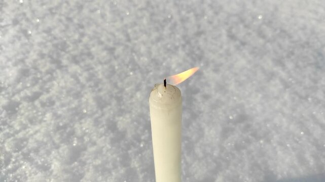 A candle burns in the snow