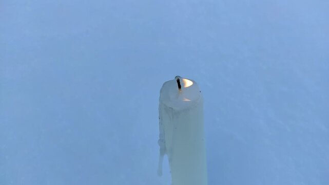 A candle burns in the snow