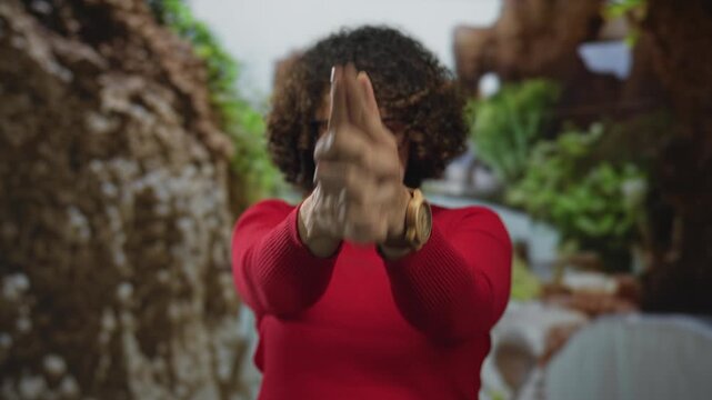 Woman wearing red sweater points finger forward in green forest; growth empowerment resilience confidence.