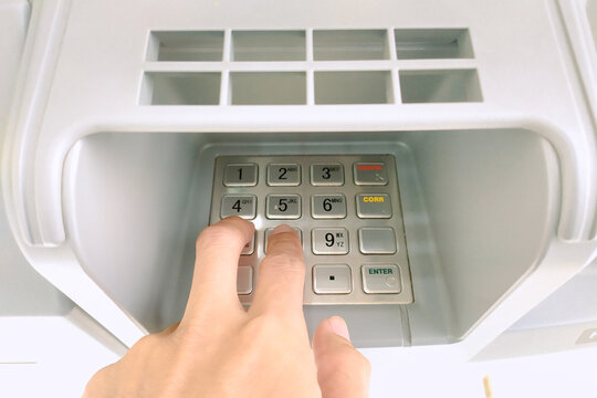Close-up of a hand entering a PIN code on an ATM keypad for a financial transaction
