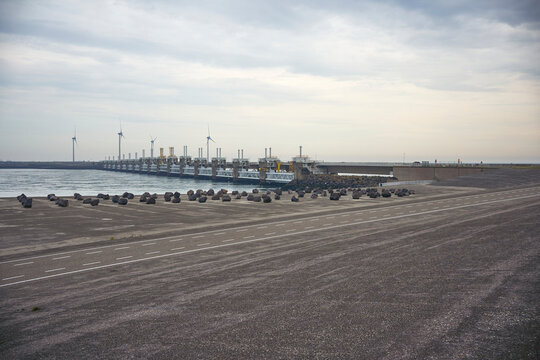 Stunning dam, deltawerke, (neeltje jans) with wind turbines and large rocks along the road, protecting the coast and generating renewable energy. Zeeland, Netherlands.