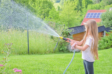 A young girl joyfully sprays water across her garden, capturing the essence of childhood play, joy, and the vitality of life through an engaging outdoor activity