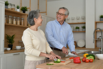 Fototapeta premium Smiling Senior Asian Couple Cooking Fresh Vegetables Together in Modern Home Kitchen, Healthy Nutrition and Active Aging Lifestyle Concept