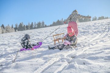 Three children trek up a snowy hill, ready for a fun day of sledding, showcasing the spirit of adventure and camaraderie in a beautiful winter scene