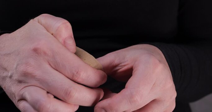 Close-up of hands applying an adhesive bandage on a small cut. First aid, wound care and medical treatment concept, focusing on hygiene and injury protection.