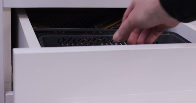 Close-up of opening a kitchen drawer and taking out a manual citrus juicer. Kitchen organization, utensils, and everyday cooking routine concept.