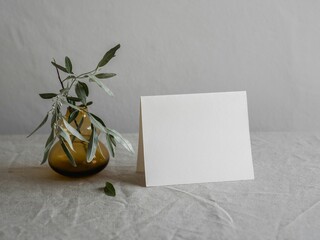 Blank White Folded Greeting Card Mockup with Olive Branch in Green Vase on Linen Background
