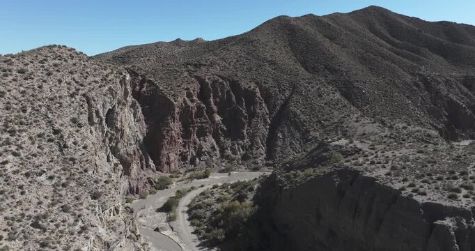 Tabernas Desert aerial along canyon wall with red rock strata showing dramatic arid geology textures and rugged ravine