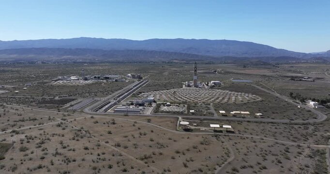 Solar Almeria PSA drone establishing over arid desert plain with solar tower and heliostat mirror field showing clean energy research infrastructure