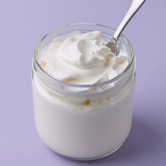 Freshly whipped white cream in a glass mason jar with silver spoon against soft purple background
