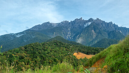 Obraz premium Many peaks Mount Kinabalu is highest tropical mountain in Borneo, jagged mountain peaks. Clouds hide in gorges. Geological rise of adolescent mountains continues. Landscape of once Mysterious Island