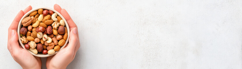 Mixed nuts bowl held by hands close up with variety of almonds cashews hazelnuts and walnuts on white background healthy snack concept