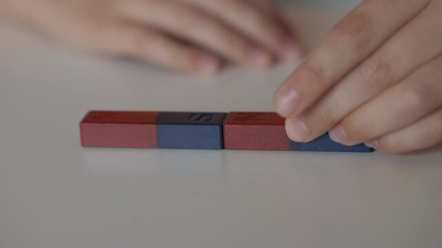 School Science Educational Experiment With Magnets. Child Hands Moves Two Magnets Around So That They Attract And Repel Each Other. Magnetic Force Demonstration Showing Attraction And Repulsion.