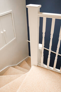 Looking down a contemporary stairwell featuring cream carpet, white painted woodworking, and a dark blue accent wall