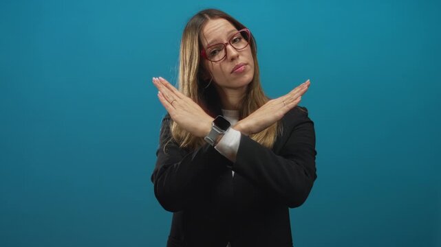 Woman wearing red glasses and black blazer with arms crossed x and hands visible in blue studio; rejection.