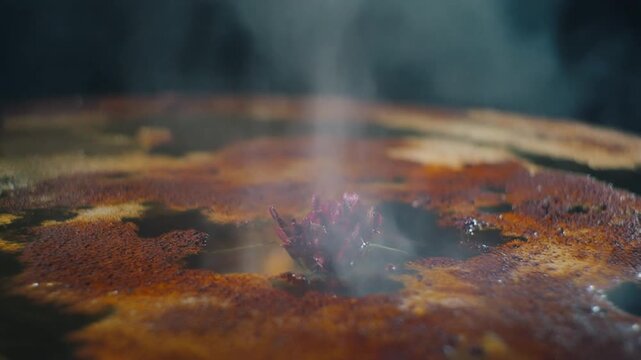 Closeup of sizzling bacon cooking on a hot griddle with steam rising.