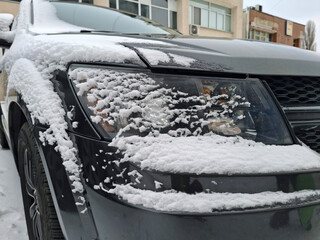 Snow is resting on the right side of the black car