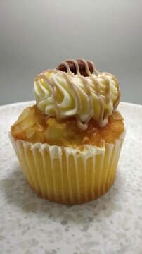 Close up of a Salted Caramel Cupcake with Buttercream and Almond Garnish Spinning on a Plate