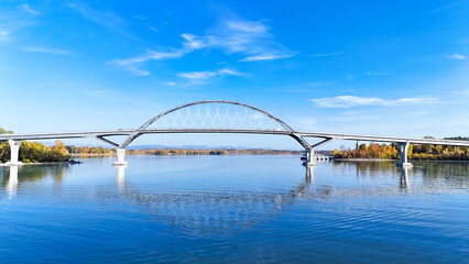 Crown Point Bridge spanning Lake Champlain between New York State and Vermont in autumn. View from middle of lake. Blue sky, water, and reflections.  