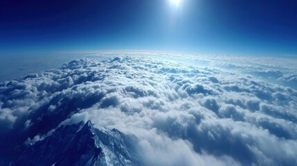 Aerial perspective captures brilliant sunshine above thick layers of white clouds obscuring mountain peaks