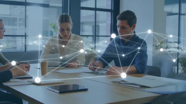 Modern office interior showing people working. Network connections overlayed on table top.