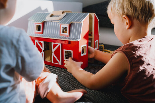 Two toddlers sitting on floor and playing with wooden farm toys. Montessori education. Motor skills, early preschool learning concepts. Happy childhood. Children playing at home