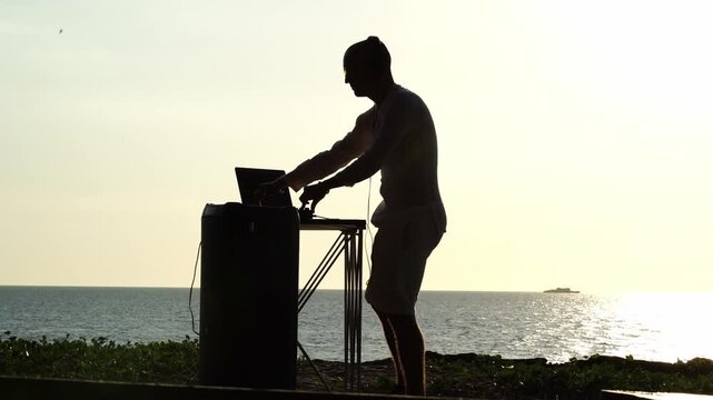 DJ playing music on the beach during sunset