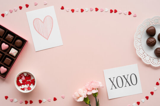 Valentine's Day, love concept. Mock up frame made of confetti, heart symbol accessories, sweets, postcards on pink background. Flat lay, top view. 
