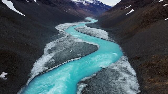 8K Glacial Realism: Cinematic vertical drone loop of a winding frozen river with shimmering blue water and mountain backdrop